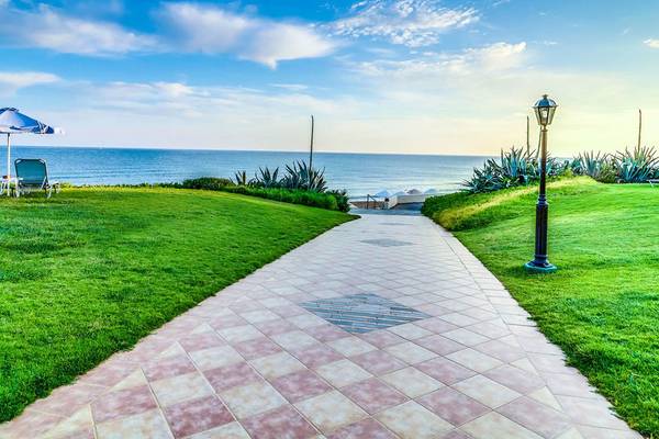 Strandweg des Creta Royal Hotels mit Blick auf das Meer und Rasen.