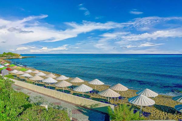 Strandansicht des Creta Royal - Adults Only Hotels mit vielen Sonnenschirmen und blauem Meer