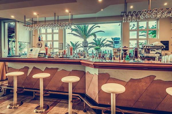 Innenansicht der Bar im Creta Royal Hotel mit Palmen im Hintergrund und vielen Getränken auf dem Tresen.