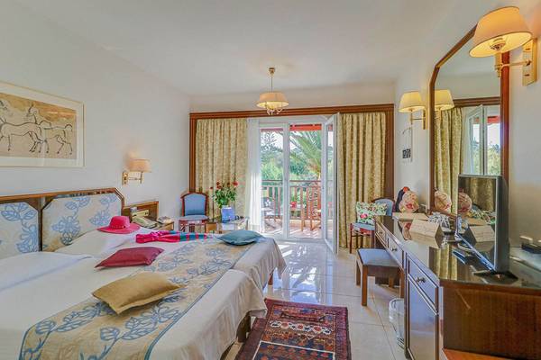 Doppelbettzimmer im Creta Royal Hotel mit Balkon und Blick auf Palmen.