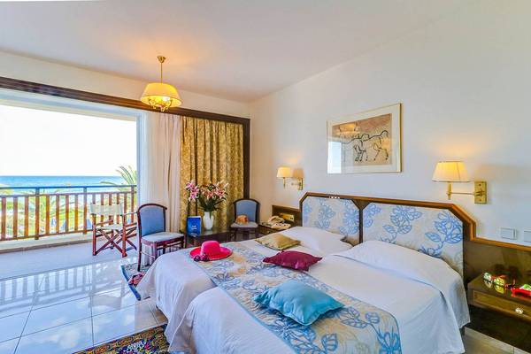 Doppelzimmer im Creta Royal Hotel mit Balkon und Meerblick, inklusive zwei Betten, einem Tisch und Stühlen.