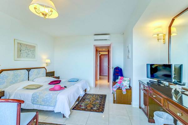 Schlafzimmer im Creta Royal Hotel mit zwei Betten, Nachttischen, einem Kleiderschrank und einem Fernseher.