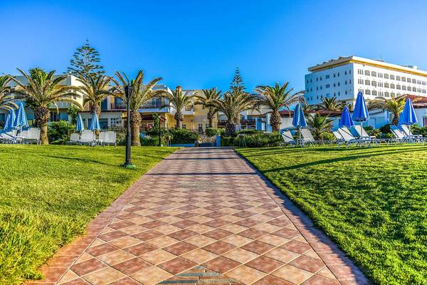 Eingang des Creta Royal - Adults Only Hotels mit gepflastertem Weg und Sonnenliegen.