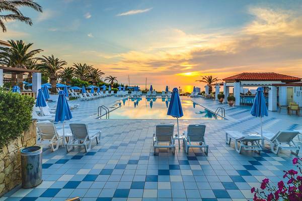 Sonnenuntergang am Poolbereich des Creta Royal Hotels - Adults Only mit Lounge-Stühlen und Sonnenschirmen