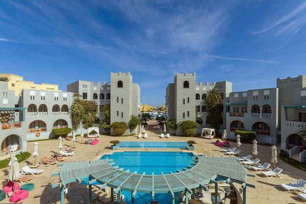 Außenbereich des Fanadir Hotel El Gouna mit Swimmingpool, Loungeliegen und Bäumen.