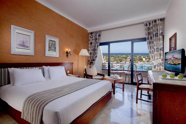Schlafzimmer im Pharaoh Azur Resort mit einem großen Bett, einem Schreibtisch, einem Fernseher und einem Blick auf den Pool.