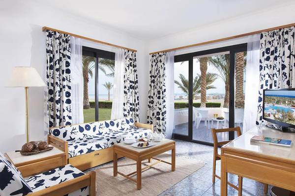 Wohnzimmer im Pharaoh Azur Resort mit Möbeln, Fernseher, Tisch, Stühle und Palmen draußen