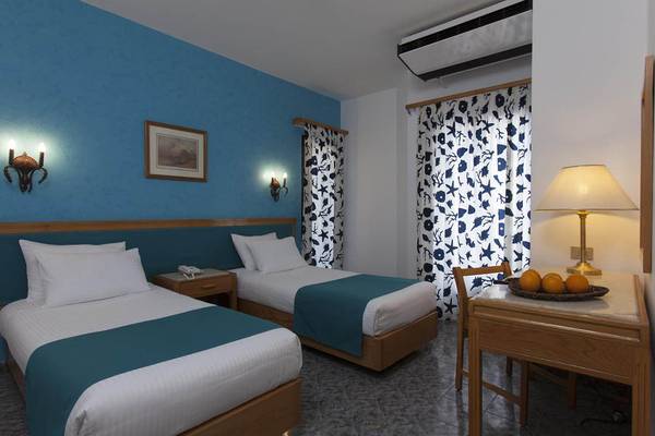 Zweibettzimmer im Pharaoh Azur Resort mit blauen Wänden, Bettwäsche und Früchten auf dem Tisch.
