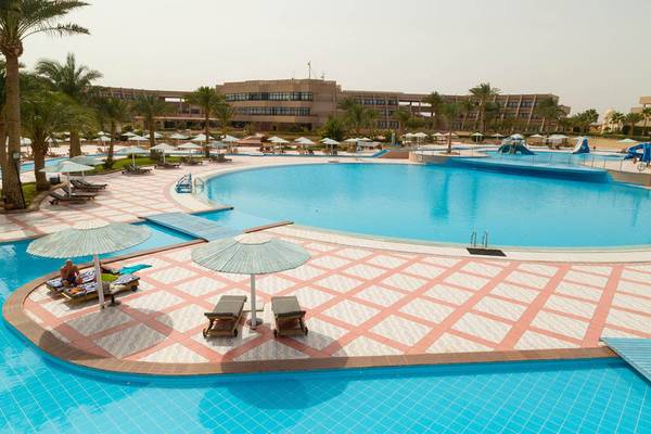 Außenansicht des Schwimmbads im Pharaoh Azur Resort mit vielen Sonnenschirmen und Liegestühlen.