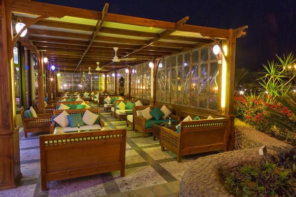 Nachtansicht des Pharaoh Azur Resort Restaurants mit beleuchteten Holzmöbeln und Pflanzen.