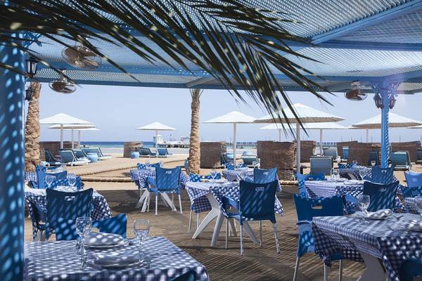Strandrestaurant im Pharaoh Azur Resort mit blauen Stühlen und Tischen unter Sonnenschirmen.