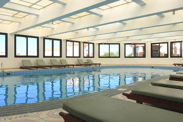 Innenpool im Pharaoh Azur Resort mit Sonnenliegen und großen Fenstern.