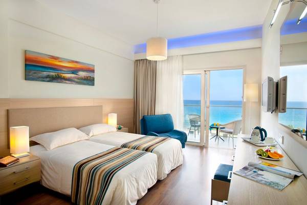 Doppelzimmer im Pernera Beach Hotel mit Meerblick, zwei Betten, Balkon und moderner Einrichtung.