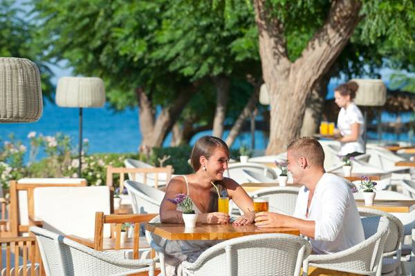 Paar im Restaurant des Pernera Beach Hotels, sitzend mit Getränken und Blick auf das Meer