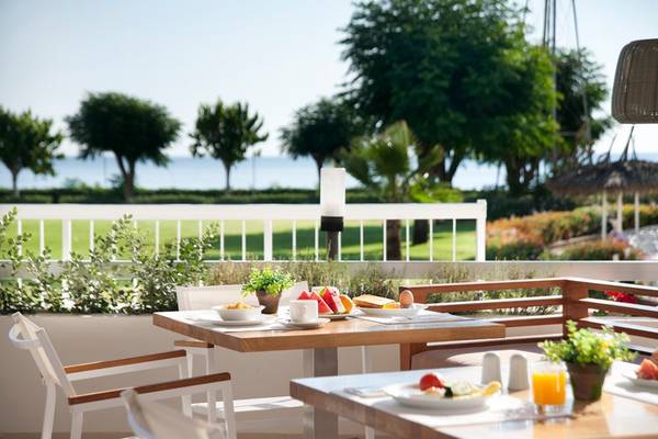 Frühstückstisch auf dem Balkon des Pernera Beach Hotels mit Blick auf einen Golfplatz und das Meer.
