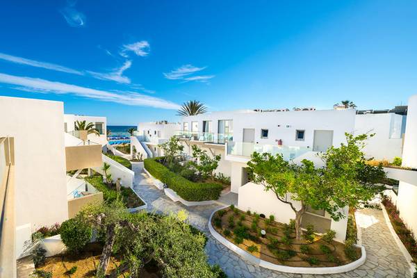 Aussenansicht des Adele Beach Hotels mit weissen Gebaeuden und Gartenanlage