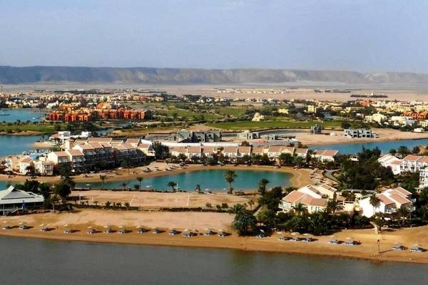 Luftaufnahme des Mövenpick Resort & Spa El Gouna mit Gebäuden, Wasser und Bergen im Hintergrund.