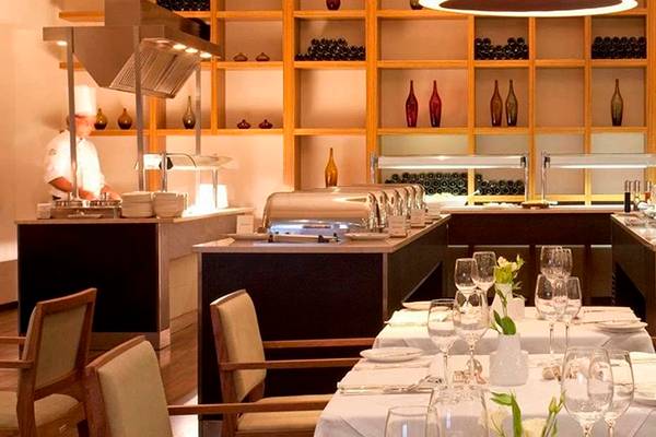 Innenbereich des Alion Beach Hotel Restaurants mit gedeckten Tischen, Geschirr und Köchen hinter einer Theke.