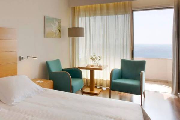 Schlafzimmer im Alion Beach Hotel mit Blick auf das Meer und modernen Möbeln.