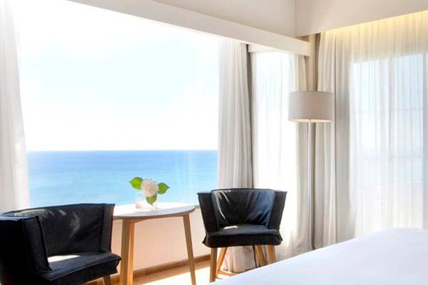Zimmer im Alion Beach Hotel mit Blick auf das Meer und modernen Möbeln.
