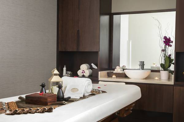 Massagebereich im Jumeira Rotana Hotel mit Tisch, Lampen, Spiegel und Blumen.