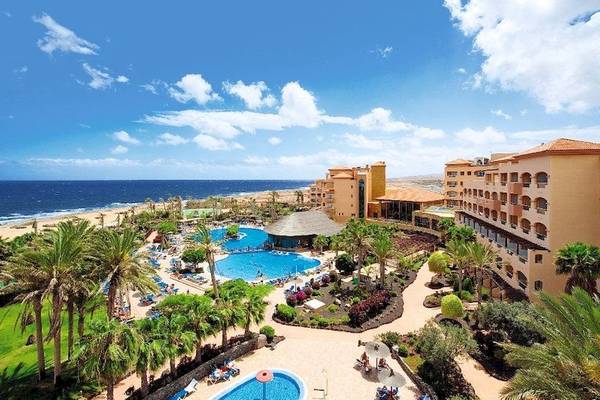 Luftaufnahme des Elba Sara Beach & Golf Resorts mit zwei Swimmingpools und einer Küstenlinie im Hintergrund.