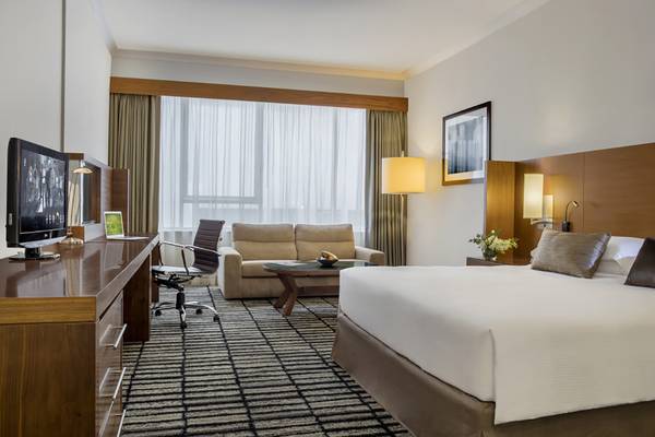 Ein elegantes Hotelzimmer im Jumeira Rotana mit einem Bett, Schreibtisch, Sofa und Fernseher.