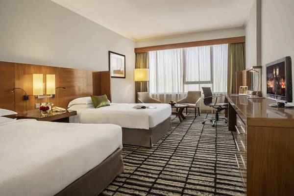 Doppelzimmer im Jumeira Rotana Hotel mit zwei Betten, Schreibtisch und Fernseher.