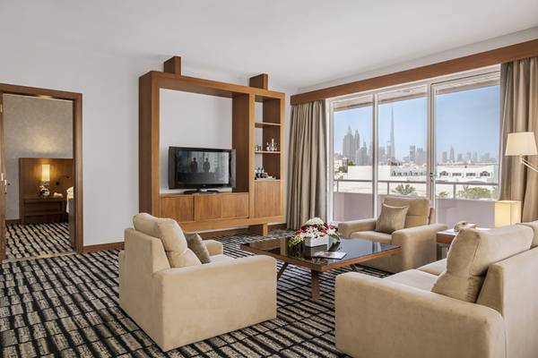 Wohnbereich der Suite im Jumeira Rotana Hotel mit Fernseher, Sofas und Stadtblick.