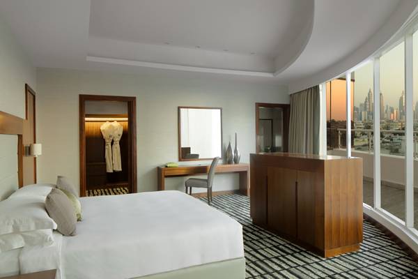Innenansicht eines eleganten Hotelzimmers im Jumeira Rotana mit Bett, Schreibtisch und großem Fenster mit Stadtblick.