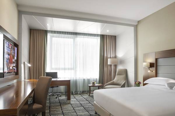Innenansicht eines Hotelzimmers im Jumeira Rotana mit Schreibtisch, Stühlen, Fenstern und Bett.
