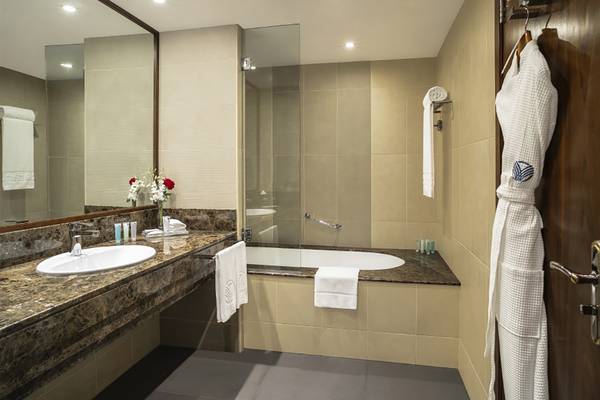 Badezimmer mit Dusche und Badewanne im Jumeira Rotana Hotel