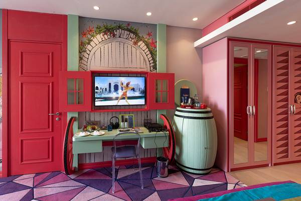 Hotelzimmer im Land of Legends Kingdom mit rotem Dekor, Fernseher, Schreibtisch und Türme.