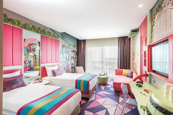 Zwei farbenfrohe Zimmer im Land of Legends Kingdom Hotel mit bunten Wänden und Musterböden.