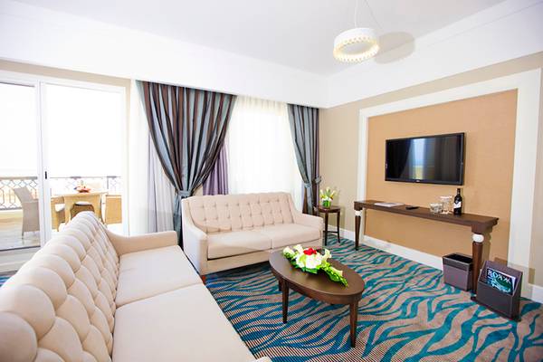Innenansicht eines Luxussuiten-Wohnzimmers im Rixos Bab Al Bahr Hotel mit zwei Sofas, einem Tisch und einer Fernsehwand.