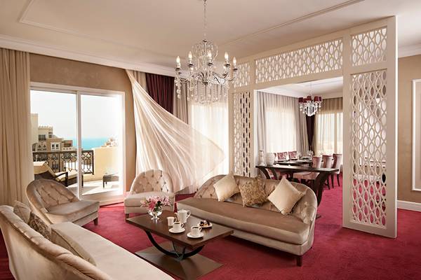 Innenansicht der Hotelsuite im Rixos Bab Al Bahr mit Wohnzimmer, Essbereich und Balkon.