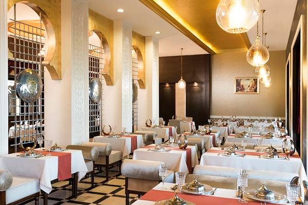 Restaurant-Interieur im Rixos Bab Al Bahr Hotel mit eleganten Tischen und goldenen Lampen.