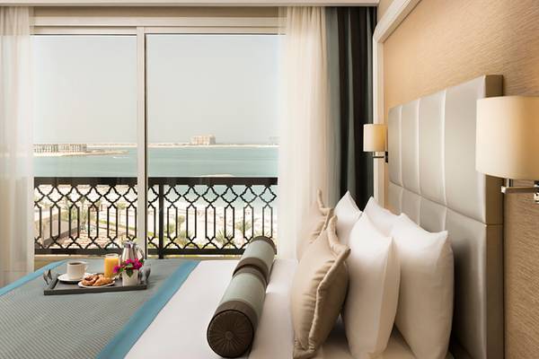 Rixos Bab Al Bahr Hotelzimmer mit Meerblick und Frühstückstablett auf dem Bett.