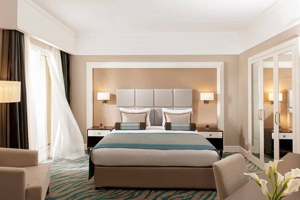Luxuriöses Hotelzimmer im Rixos Bab Al Bahr mit Doppelbett, Nachttischen und Spiegelschrank