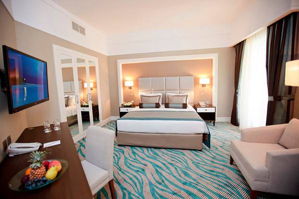 Hotelzimmer im Rixos Bab Al Bahr mit Bett, Fernseher, Schreibtisch und Obstteller.