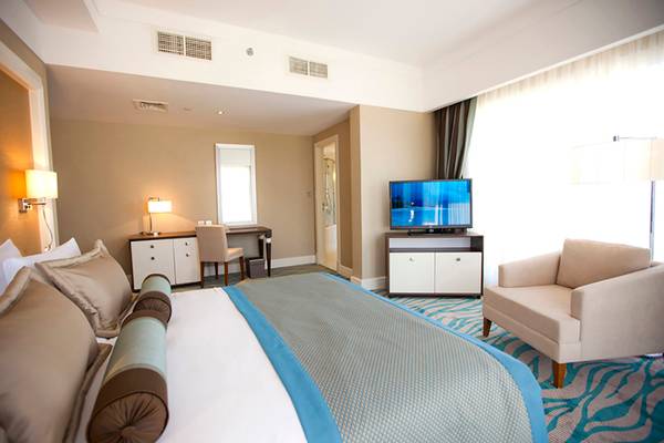 Rixos Bab Al Bahr Hotelzimmer mit Bett, Fernseher und Schreibtisch.