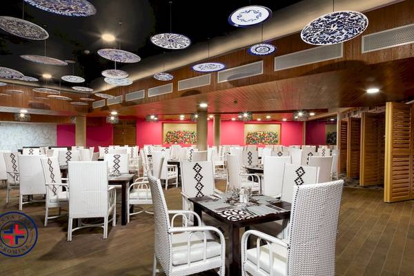 Innenansicht des Restaurants im Grand Sirenis Punta Cana Resort mit weißen Stühlen und Tischen.