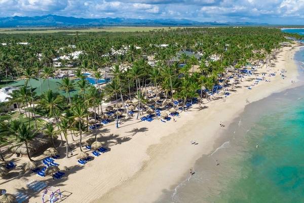 Luftaufnahme des Grand Sirenis Punta Cana Resorts mit vielen Palmen, Sonnenliegen und einem blauen Ozean.