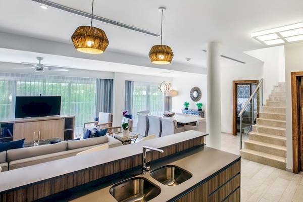 Wohnbereich im Grand Sirenis Punta Cana Resort mit Fernseher, Sofa, Esstisch und Küchenbereich.