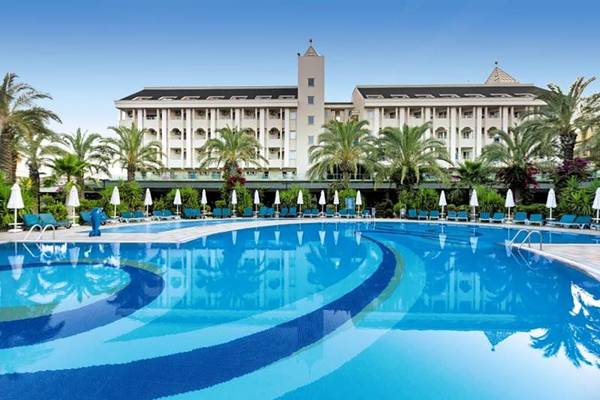 Außenpool des Calimera Hane Garden Hotels mit Lounge-Liegen und Palmen.