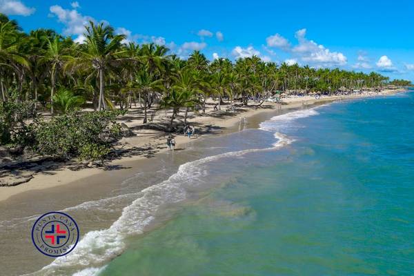 Strandansicht des Grand Sirenis Punta Cana Resorts mit Palmen und blauem Wasser.