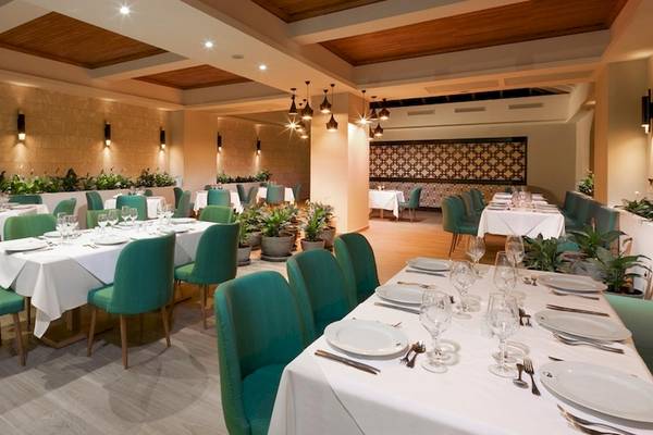 Das Grand Sirenis Punta Cana Resort verfügt über ein elegantes Restaurant mit grünen Stühlen und weißen Tischdecken.