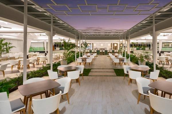 Innenansicht des Restaurants im Grand Sirenis Punta Cana Resort mit Tischen und Stühlen unter einem Dach.