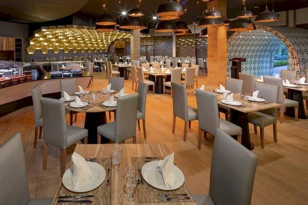 Innenansicht des Restaurants im Grand Sirenis Punta Cana Resort mit hölzernen Tischen und Stühlen.