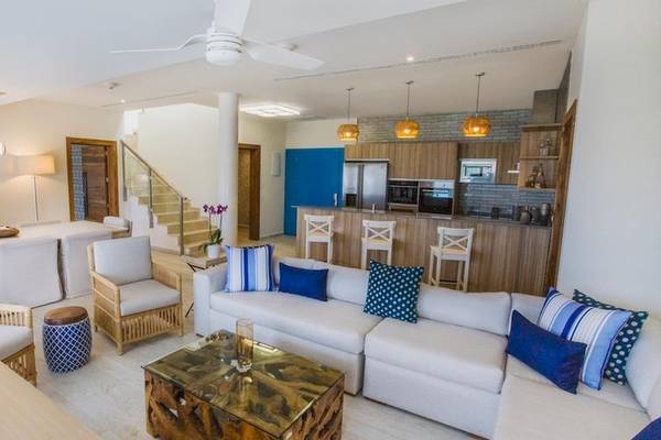 Wohnzimmer im Grand Sirenis Punta Cana Resort mit offener Küche, Esstisch und Sofas.